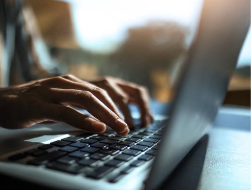 Close-up of hands typing on a laptop keyboard.