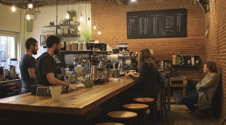 Baristas and customers inside a small espresso bar.